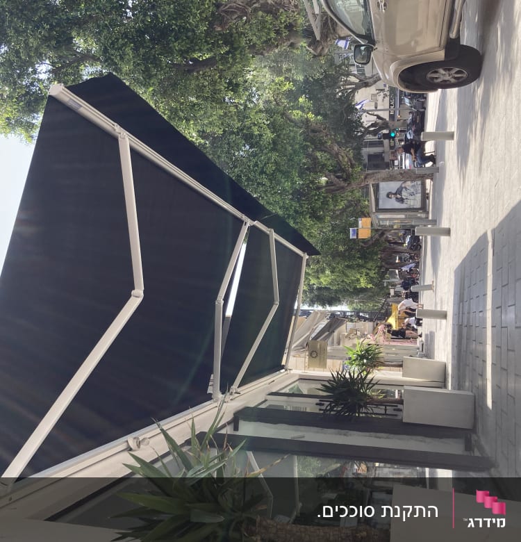 סוכך שחור עם זרועות מתכת לבנות ברחוב עירוני